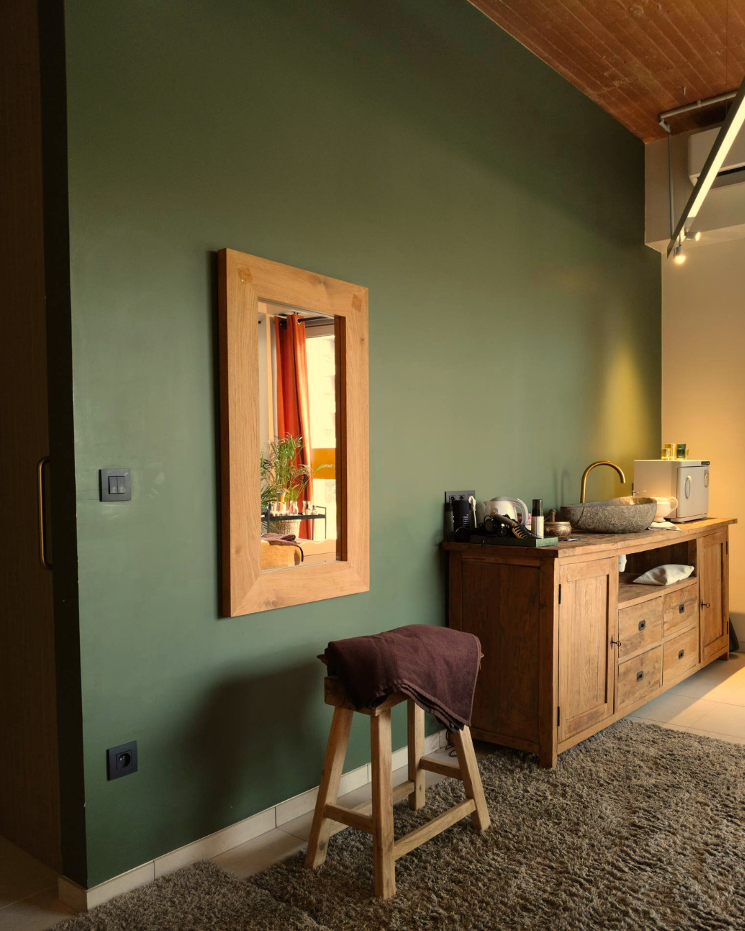 Rustige behandelruimte met groene wand en houten meubel